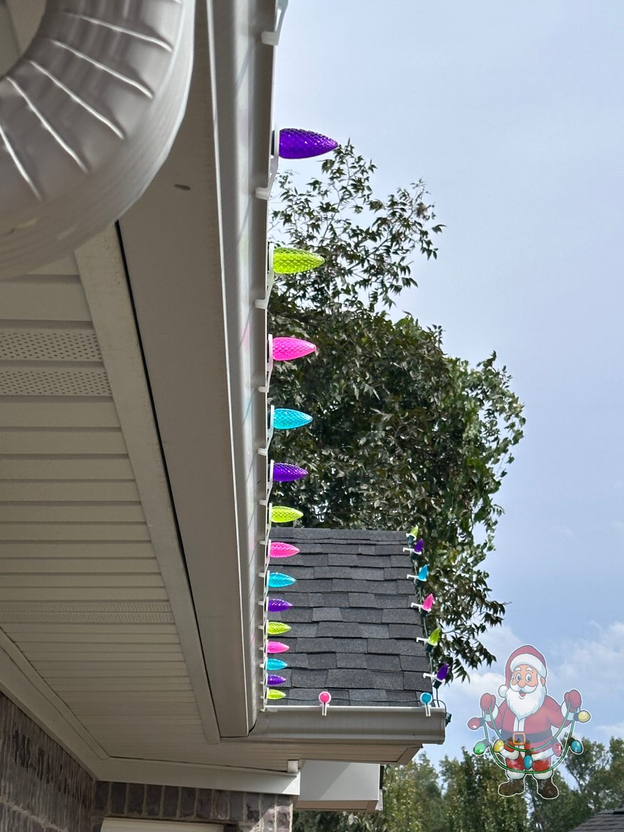 Multicolor C9 Christmas lights clipped to a home gutter during install